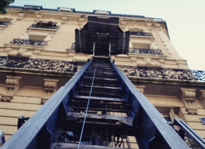 Vue en contre-plongée d'un monte-meuble en façade lors d'un déménagement à Paris